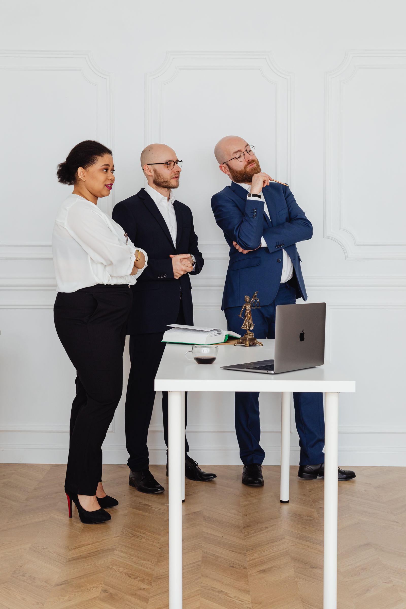 Tres profesionales jurídicos de pie en una oficina contemporánea